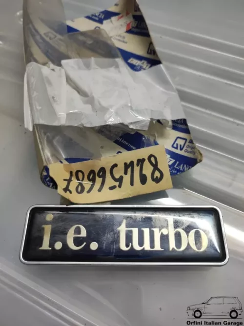 11841-82456687.webp 82456687 Badge Scritta Lancia Thema IE Turbo